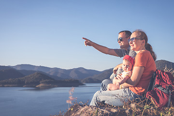 Image showing Happy family sitting near the lake at the day time.