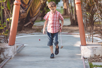 Image showing Happy little boy  playing mini golf.