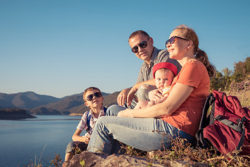 Image showing Happy family sitting near the lake at the day time.