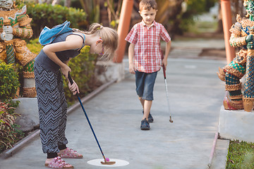 Image showing Happy brother and sister  playing mini golf.