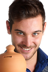 Image showing Young man holding a clay moneybox