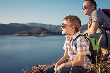 Image showing Happy family sitting near a lake at the day time.