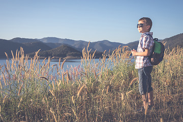 Image showing One happy little boy standing near a lake