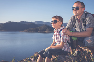 Image showing Happy family sitting near a lake at the day time.