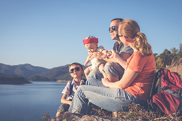 Image showing Happy family sitting near the lake at the day time.