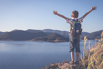 Image showing One happy little boy standing near a lake