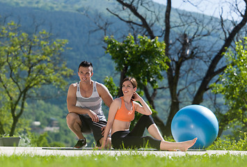 Image showing woman with personal trainer doing morning yoga exercises