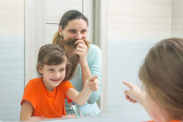 Image showing My daughter and mother are having fun looking at my mother, who put her hair to her face like a mustache