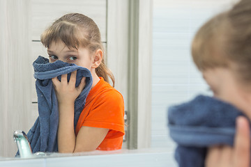 Image showing The child wipes his face with a clean towel in the bathtub