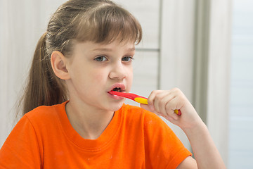 Image showing The girl is brushing her teeth in the bathroom