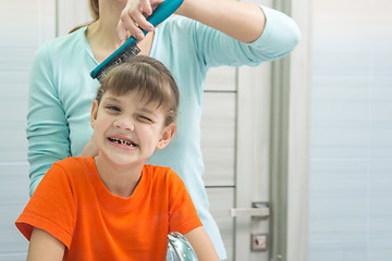 Image showing Mom combs her seven-year-old daughter in the bathroom