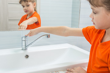 Image showing The girl closed the water from the mixer after washing