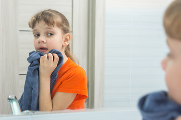 Image showing Seven-year-old girl wipes her face with a towel after washing