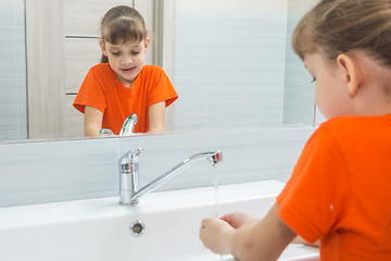 Image showing Seven-year-old girl washes face in bath