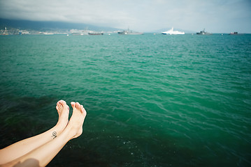 Image showing Crop female feet above sea water