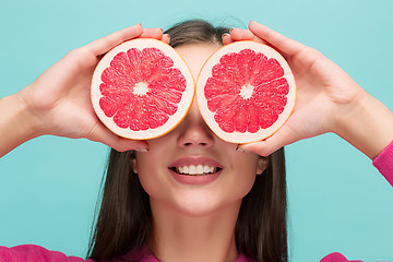 Image showing Pretty woman with delicious grapefruit in her arms.