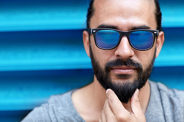 Image showing close up of man in sunglasses touching beard