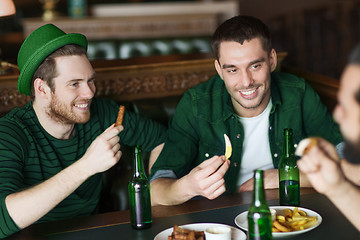 Image showing male friends drinking green beer and eating at pub
