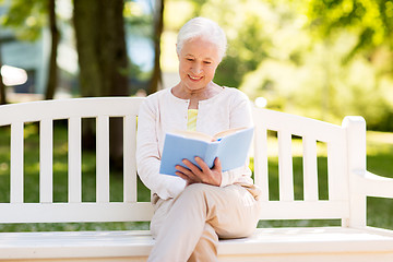 Image showing happy senior woman reading book at summer park