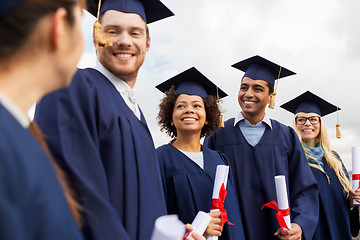 Image showing happy students in mortar boards with diplomas