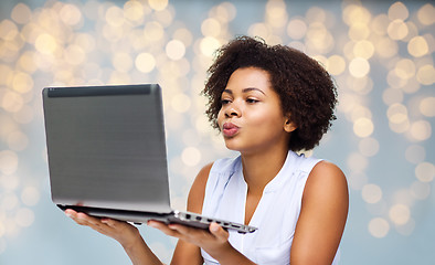 Image showing woman with laptop computer sending kiss to someone