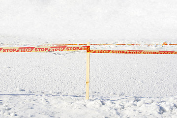Image showing Yellow STOP tape surrounded frozen ice hole