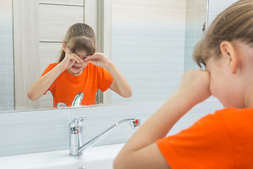 Image showing Seven-year-old girl rubs her eyes trying to wake up, washing in the morning in the bathtub