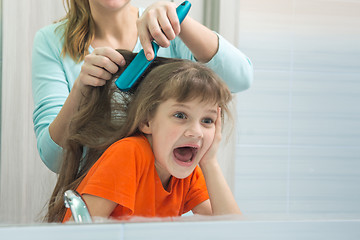 Image showing Mom and daughter are having fun while mum combing the childs hair