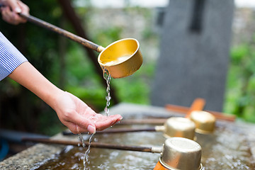 Image showing Woman using the water bamboo ladle for purification