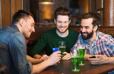 Image showing friends with smartphone drinking green beer at pub