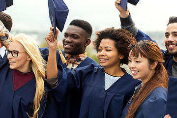 Image showing happy graduates or students waving mortar boards