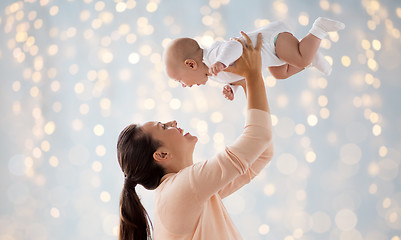 Image showing happy mother playing with little baby over lights