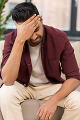 Image showing unhappy man suffering from head ache at home