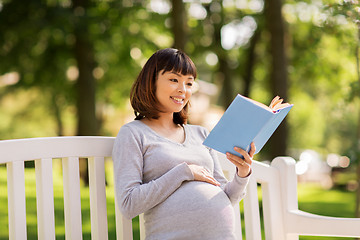 Image showing happy pregnant asian woman reading book at park