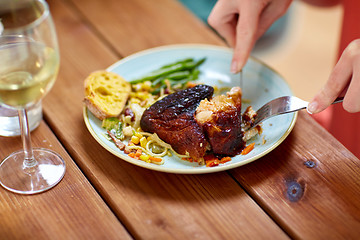 Image showing hands of woman with fork eating roast chicken