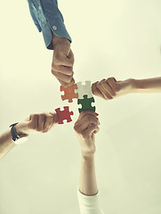 Image showing Group of business people assembling jigsaw puzzle