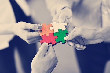 Image showing Group of business people assembling jigsaw puzzle