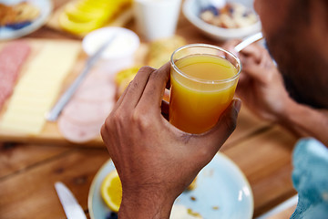 Image showing close up of male hand with glass of orange juice