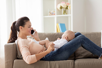 Image showing mother with baby calling on smartphone at home