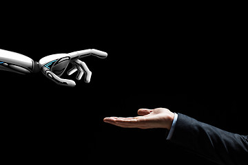 Image showing robot and human hand on black background