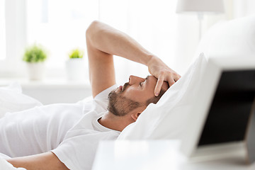 Image showing man in bed at home suffering from headache