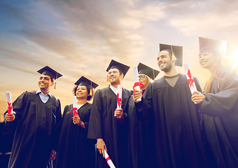 Image showing happy students in mortar boards with diplomas