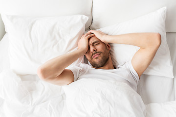 Image showing man in bed at home suffering from headache