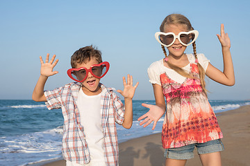 Image showing Two happy little children playing on the beach at the day time. 