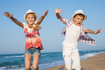 Image showing Two happy little children playing on the beach at the day time.