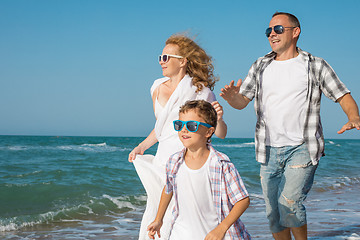 Image showing Father mother and  son  playing on the beach at the day time.