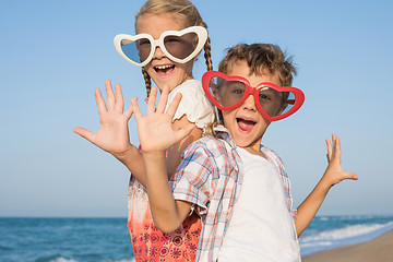 Image showing Two happy little children playing on the beach at the day time.