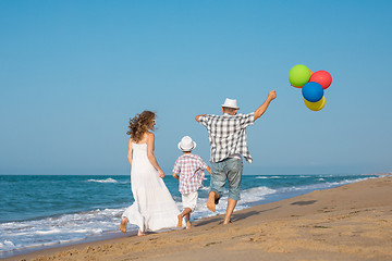 Image showing Father mother and  son  playing on the beach at the day time.