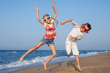 Image showing Two happy little children playing on the beach at the day time.