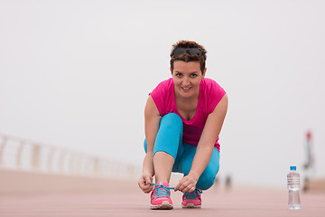 Image showing Young woman tying shoelaces on sneakers